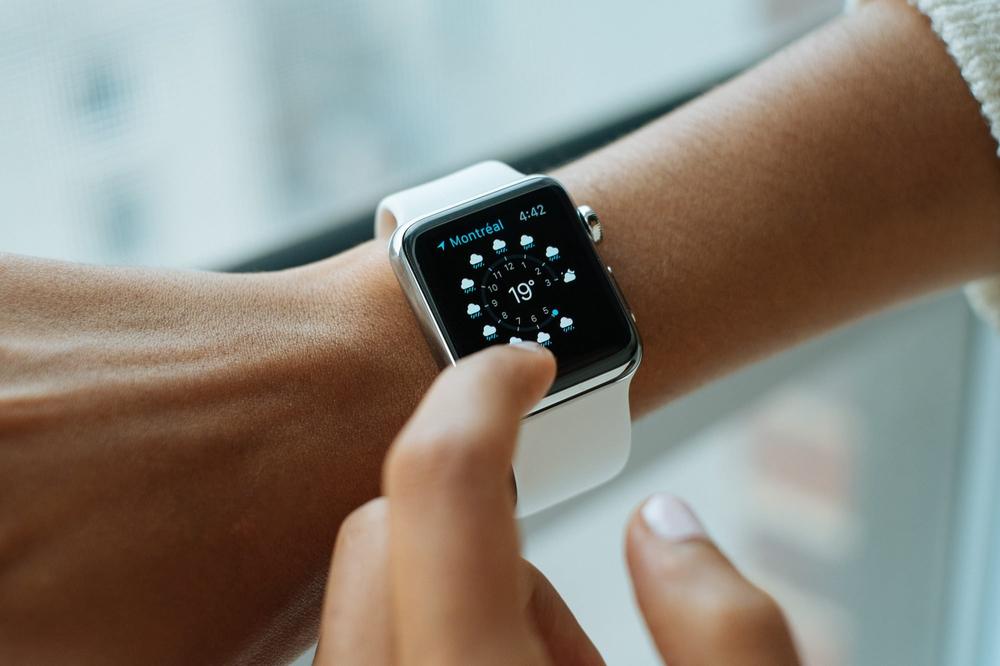 A photograph of a person wearing an Apple Watch and using the Weather app for watchOS.